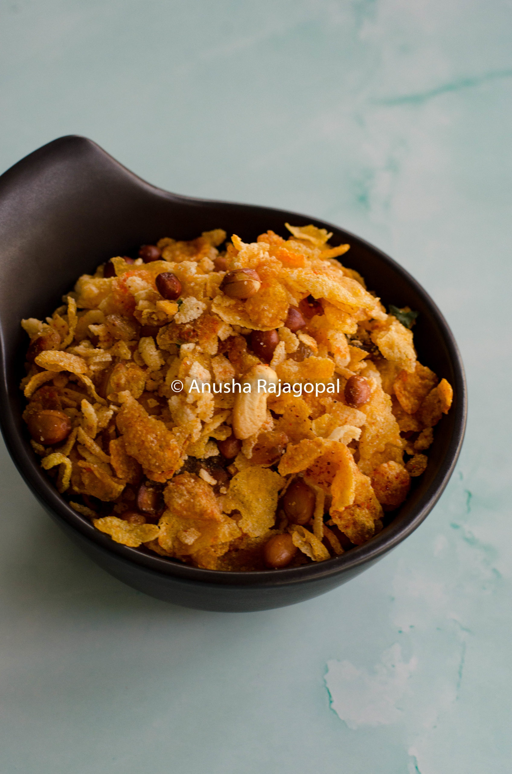 cornflakes mixture served in a black bowl against a pale blue background