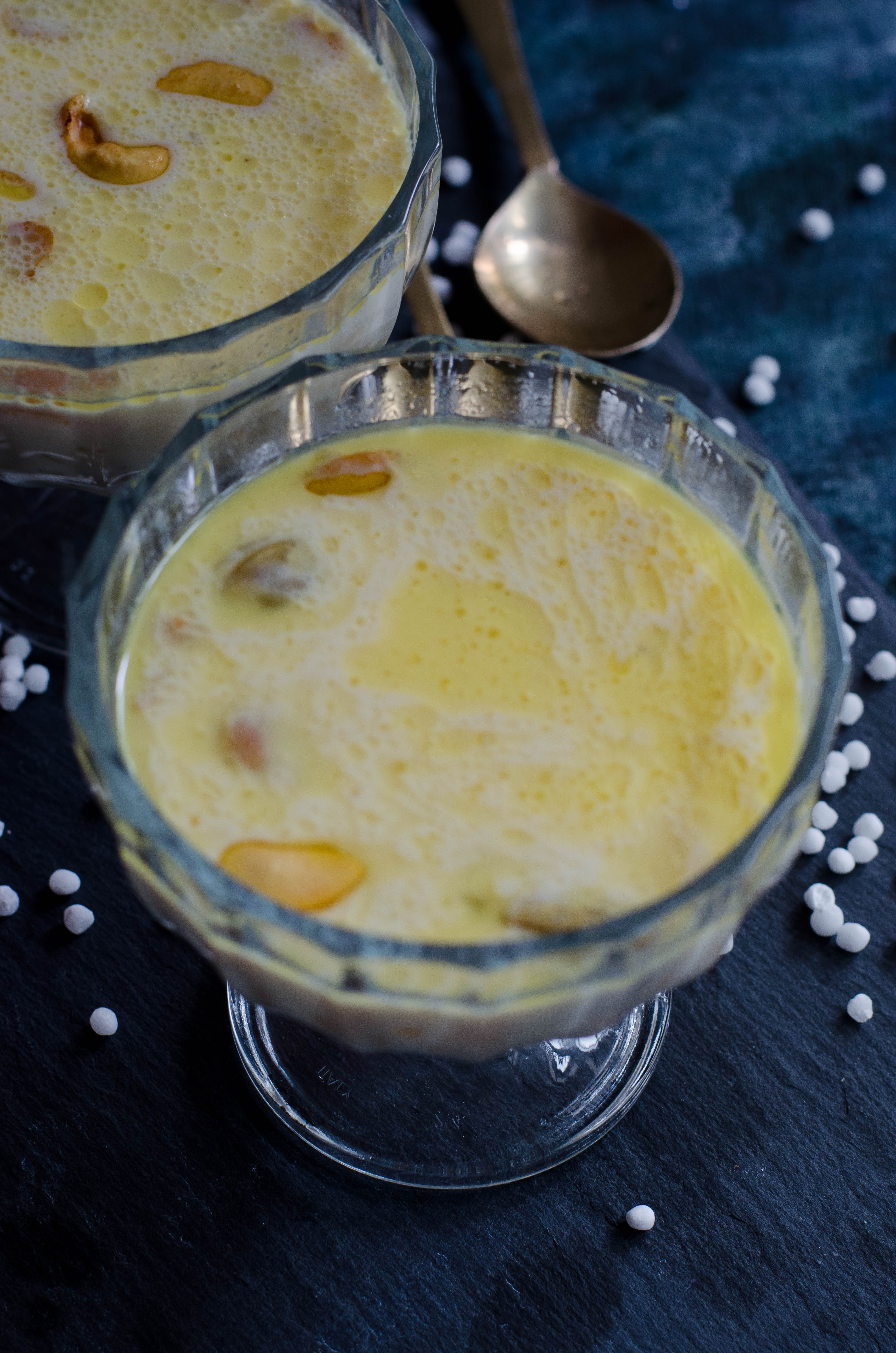 Sabudana kheer- a creamy indian dessert made with sago pearls and milk. Served in a glass bowl placed on slate board.