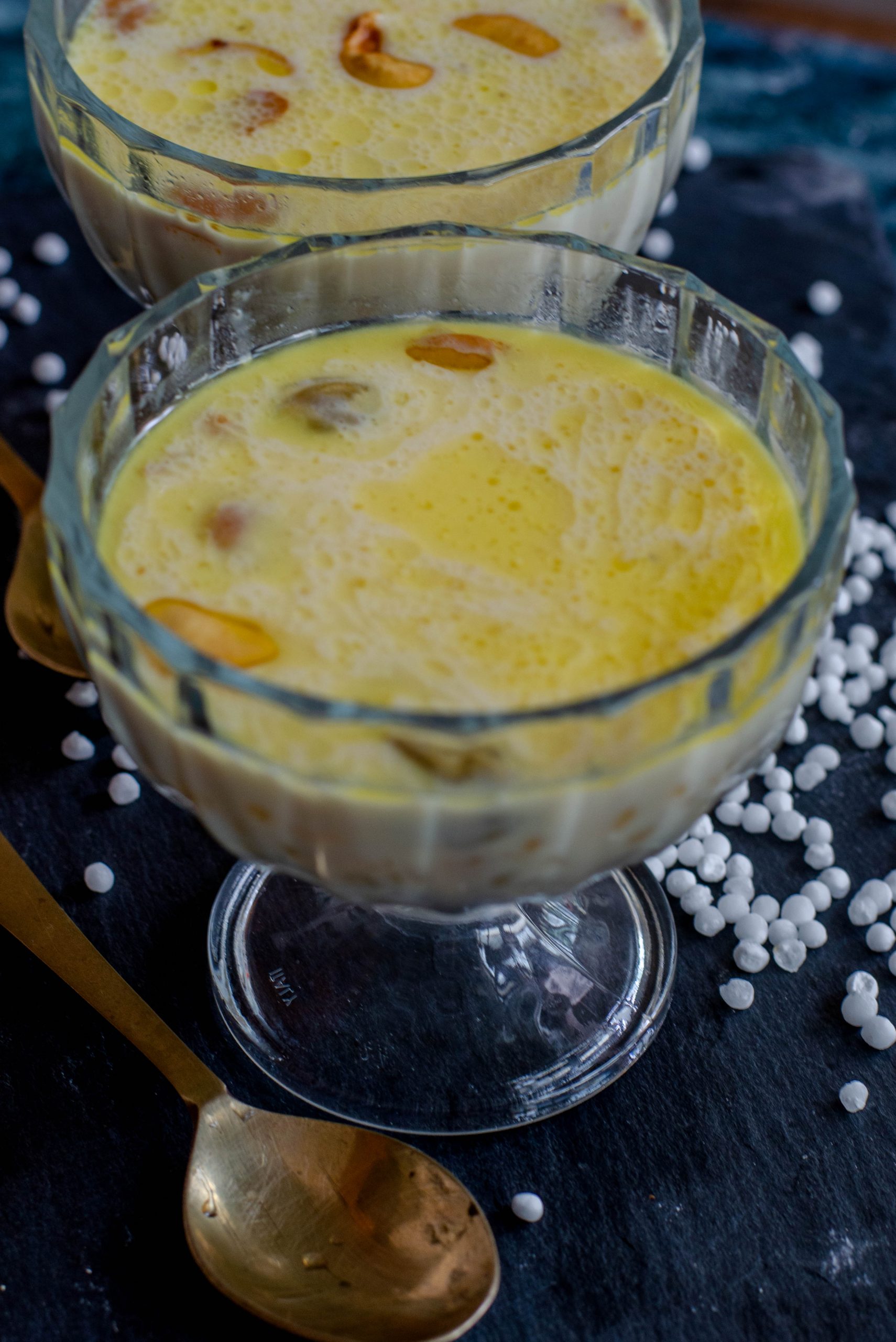 Sabudana kheer- a creamy indian dessert made with sago pearls and milk. Served in a glass bowl placed on slate board.