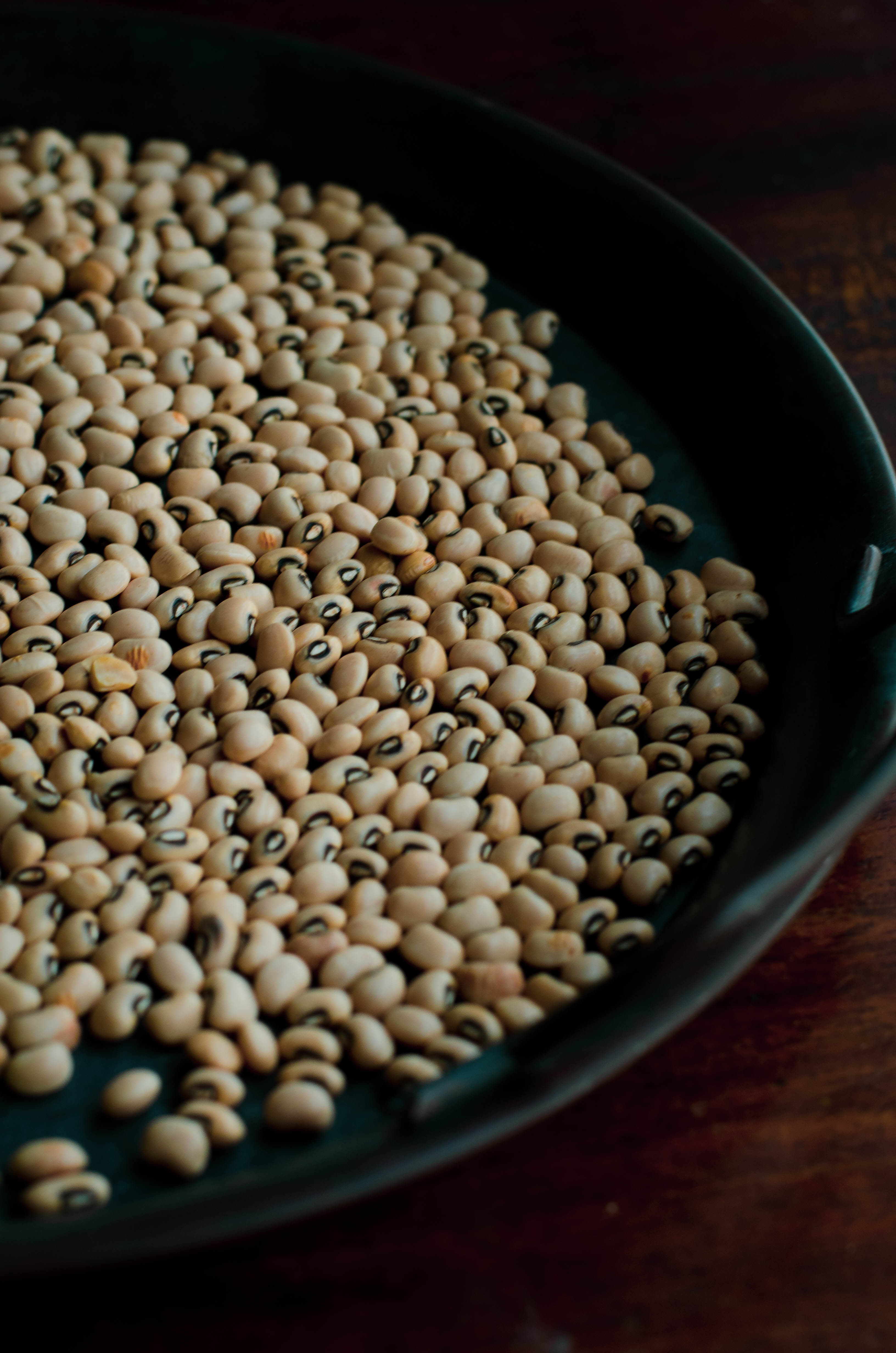 Lobia Masala -Black eyed peas curry served in a grey bowl placed on a blackish gray tray with scattered black eyed peas and cilantro at the background