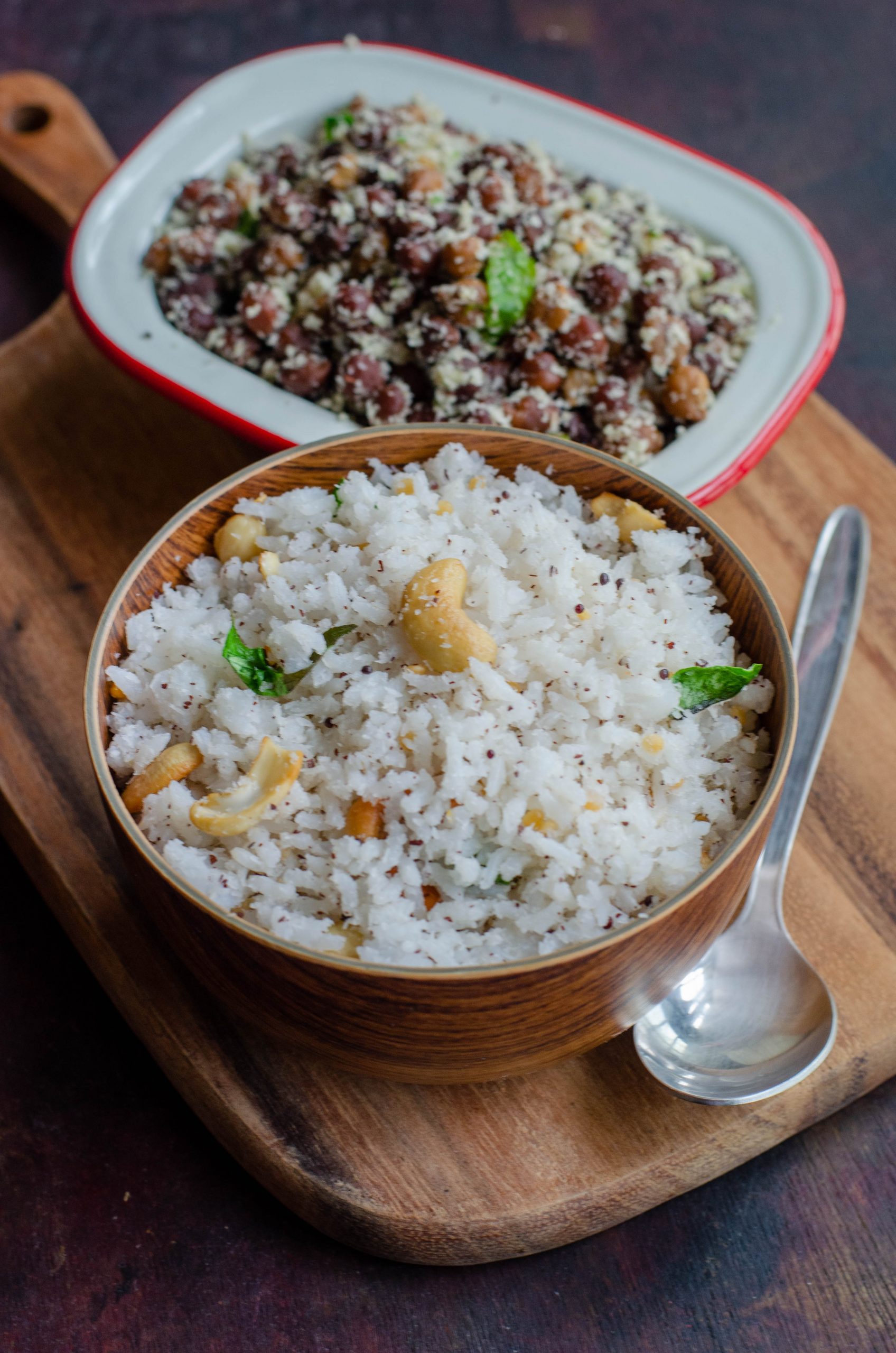 Thengai Sadam, south Indian style coconut rice served along with Kaala channa stir fry. Both placed at an angle to each other on a wooden chopping board.