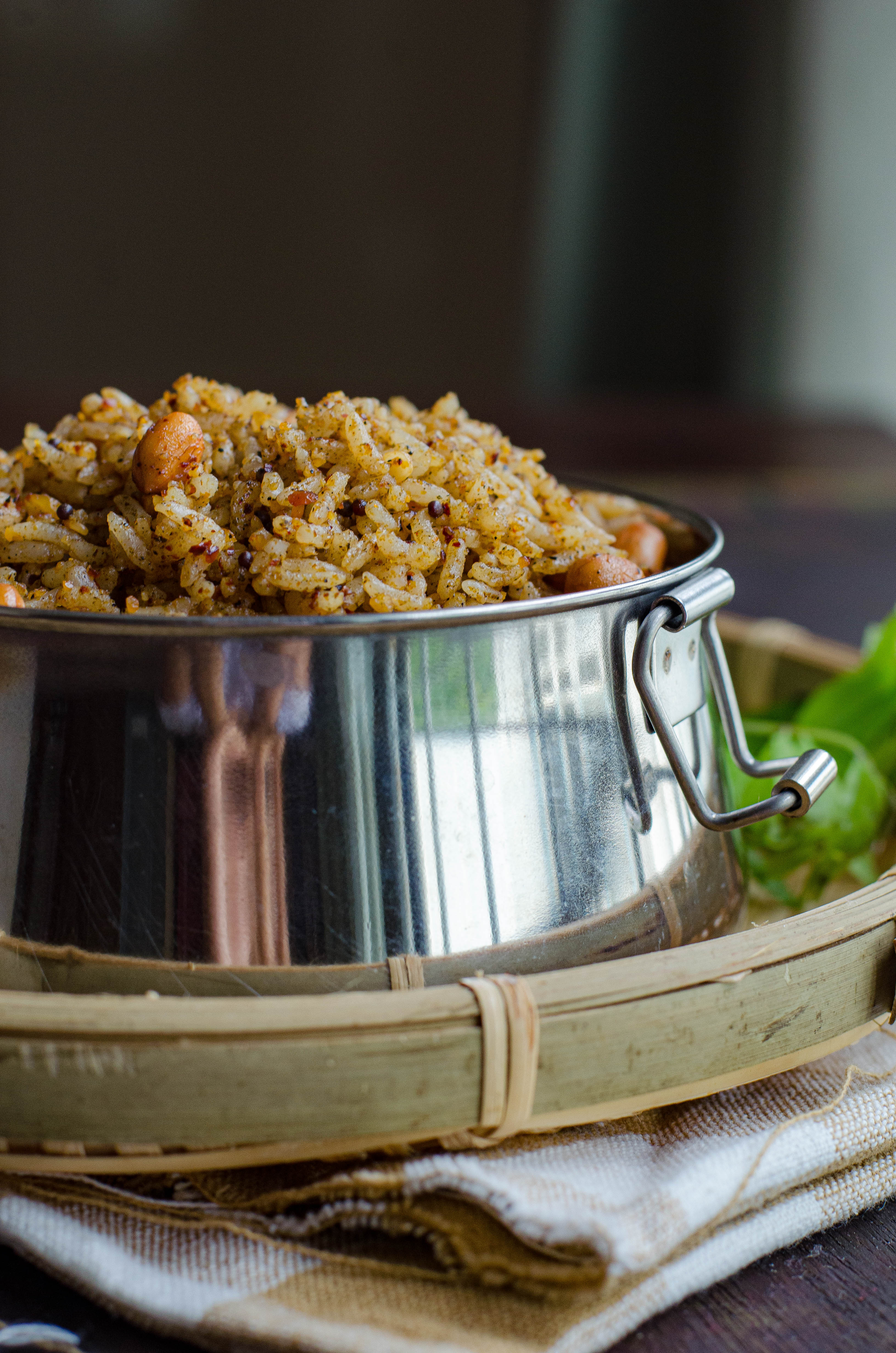 Ellu sadam- A simple vegan rice-based dish made with a sesame seeds based spice mix, served in a tiffin box placed on a bamboo basket against a brown backdrop.