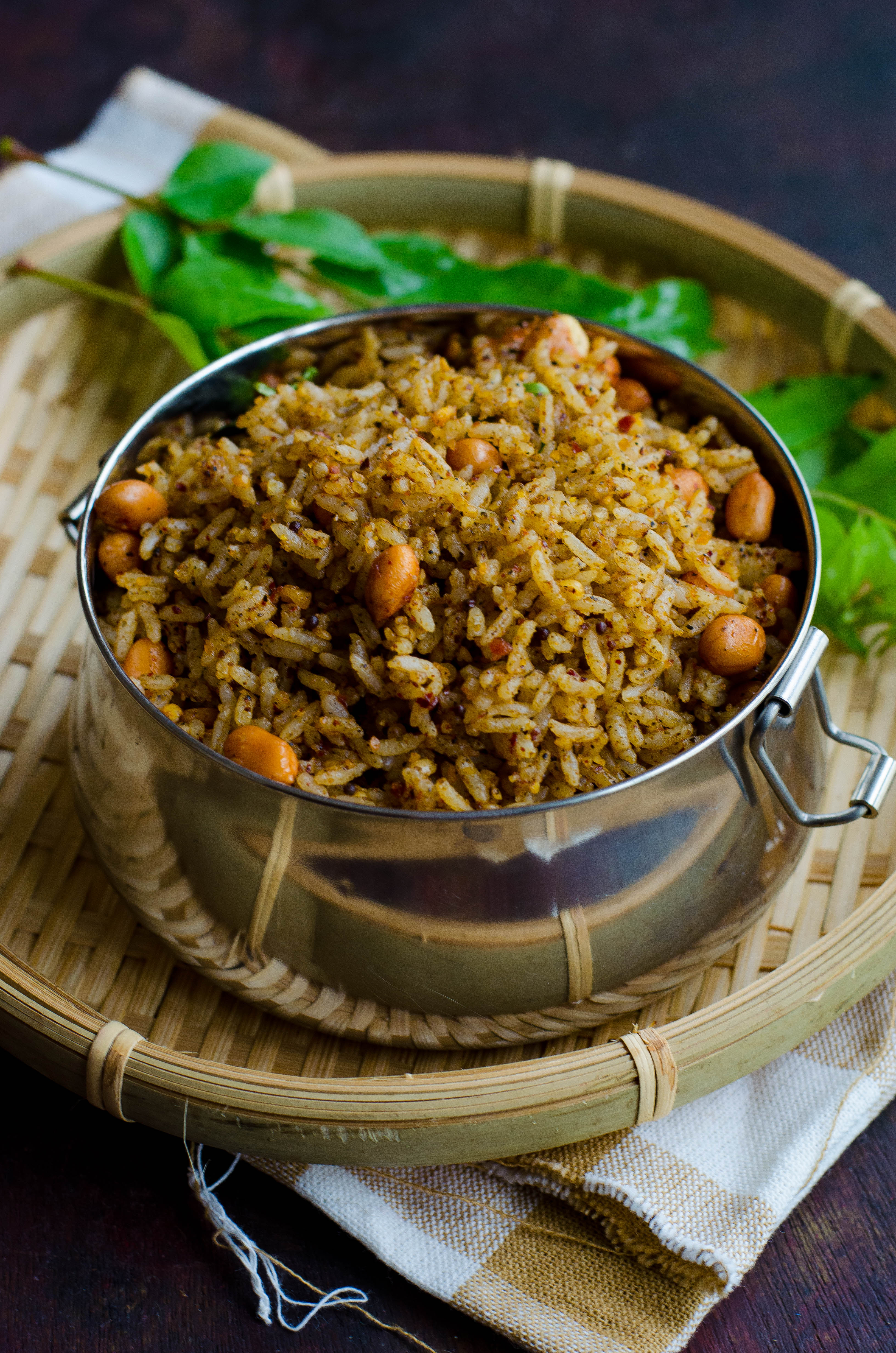 Ellu sadam- A simple vegan rice-based dish made with a sesame seeds based spice mix, served in a tiffin box placed on a bamboo basket against a brown backdrop.