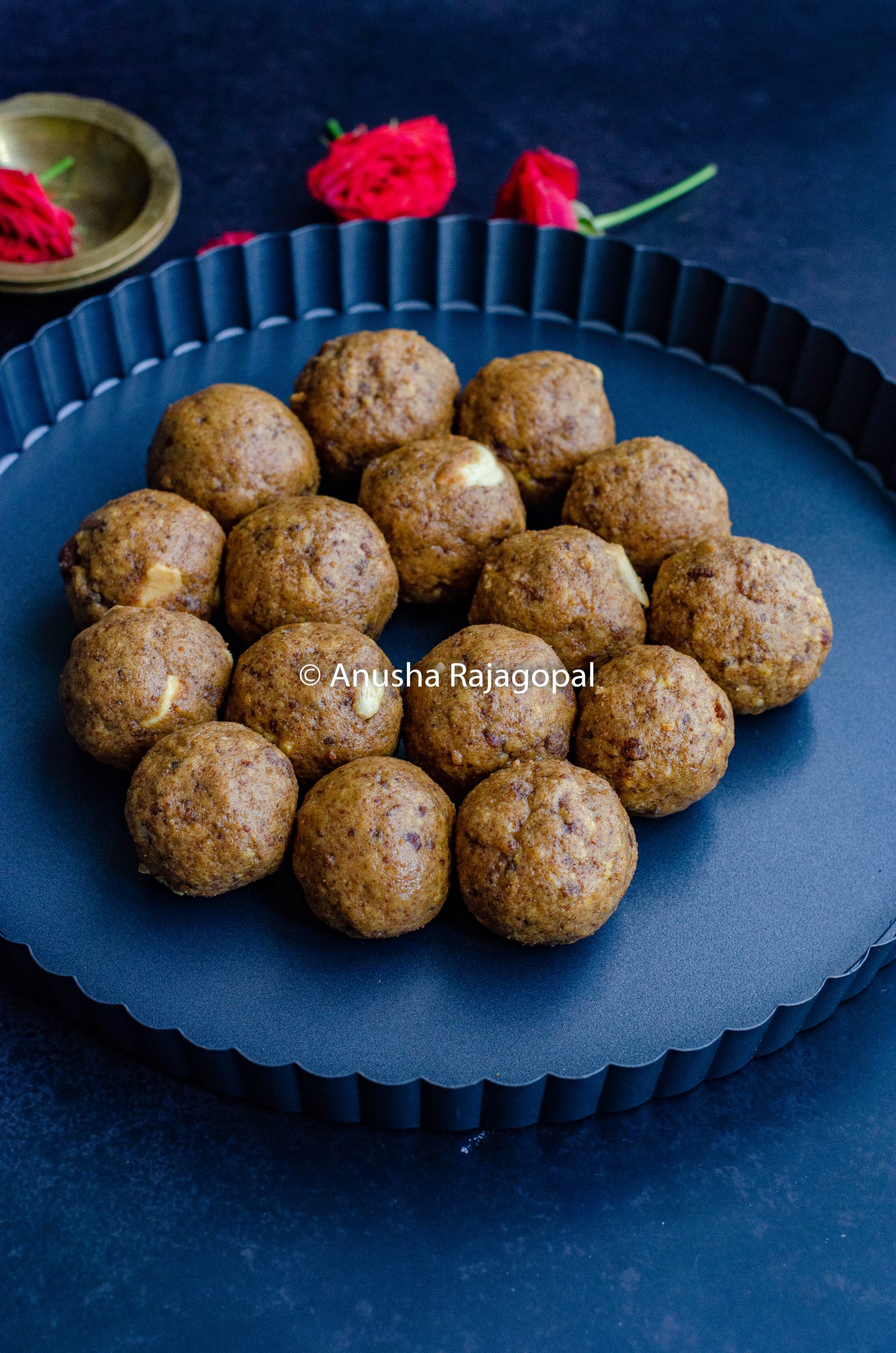 sattu ke ladoo on a black plate with rose petals in the background