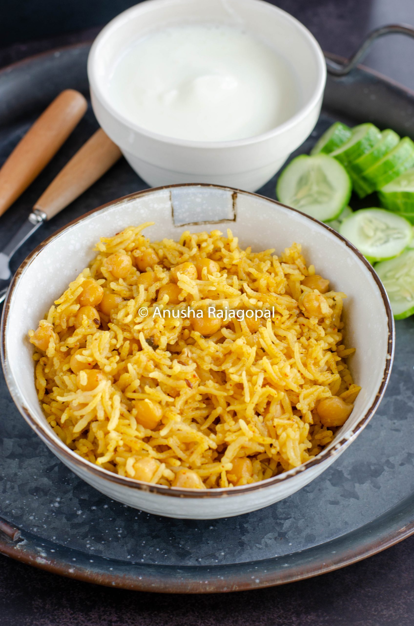 chana pulao in mealthy served in a beige bowl with cukes and raita.