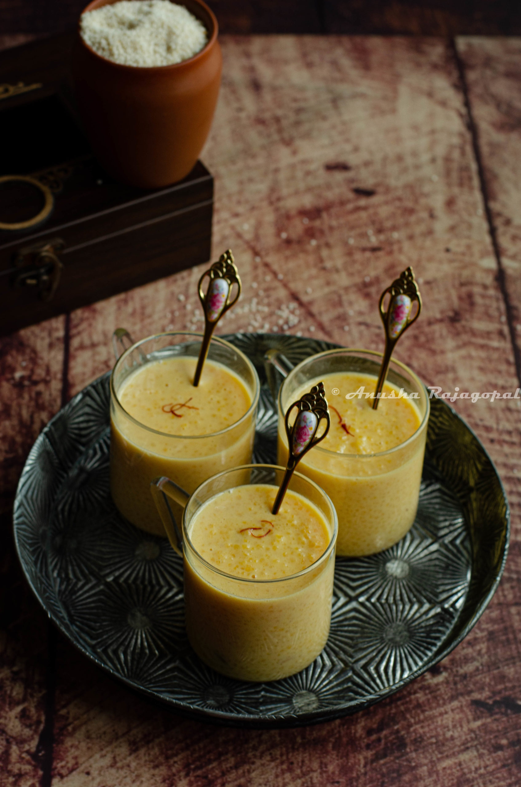 Little millet kheer served in glass mugs with tiny golden spoons in them.