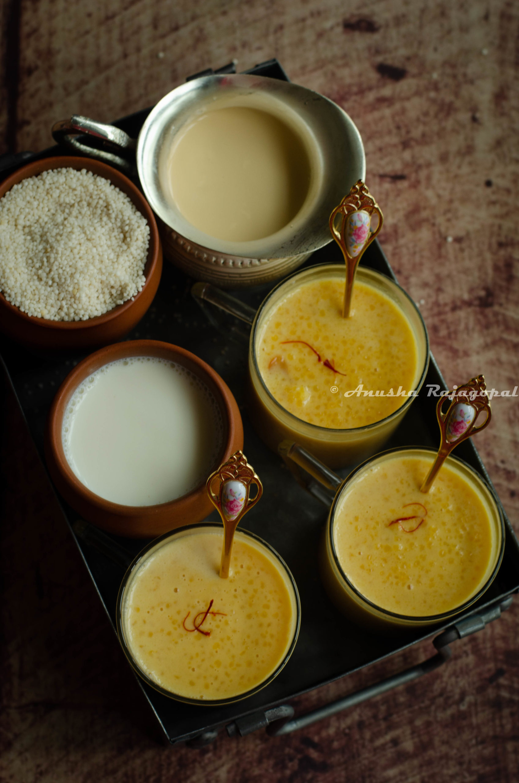 Little millet kheer served in glass mugs with tiny golden spoons in them.