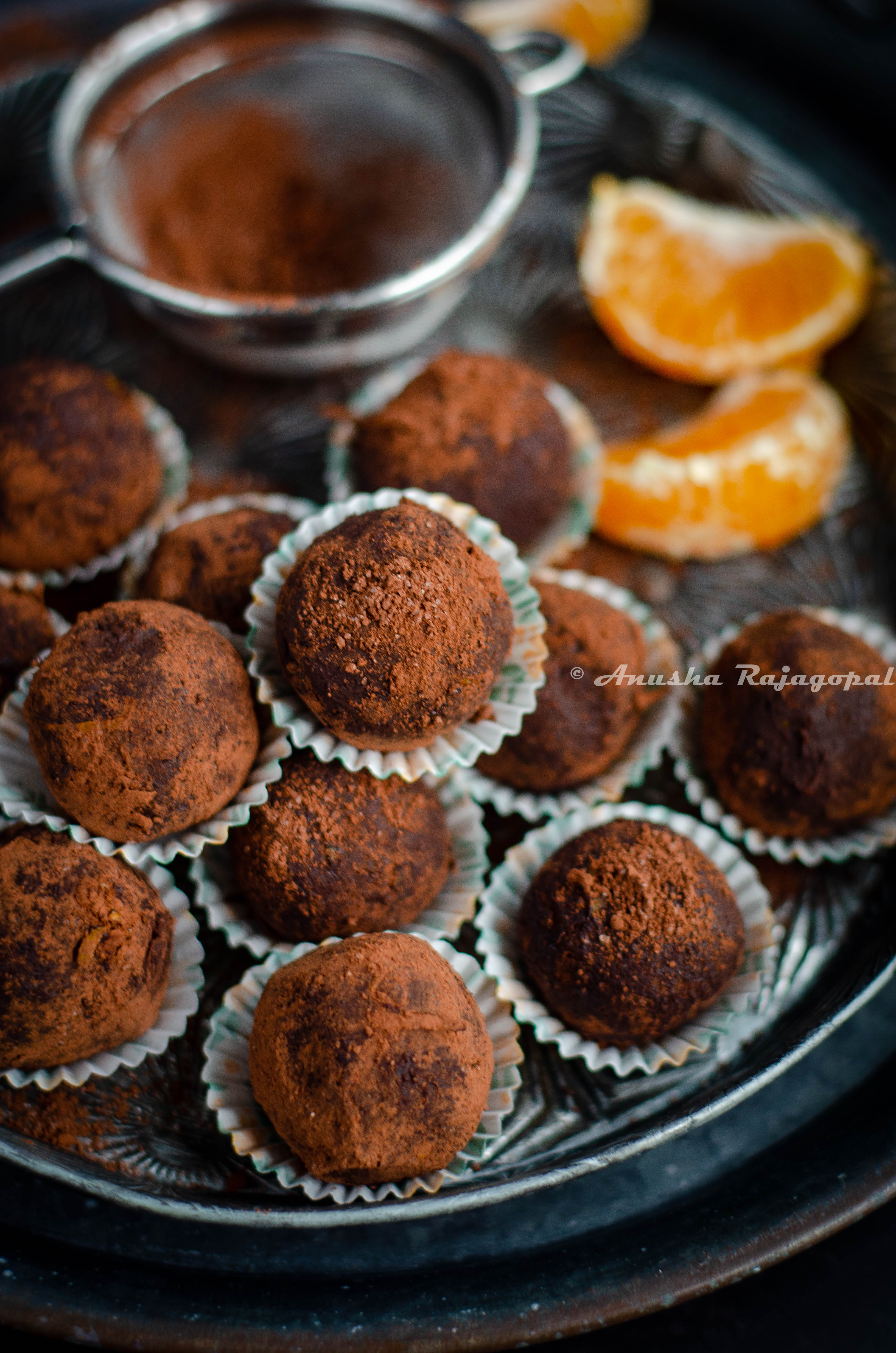chocolate orange truffles in liners stacked on a vintage metal plate