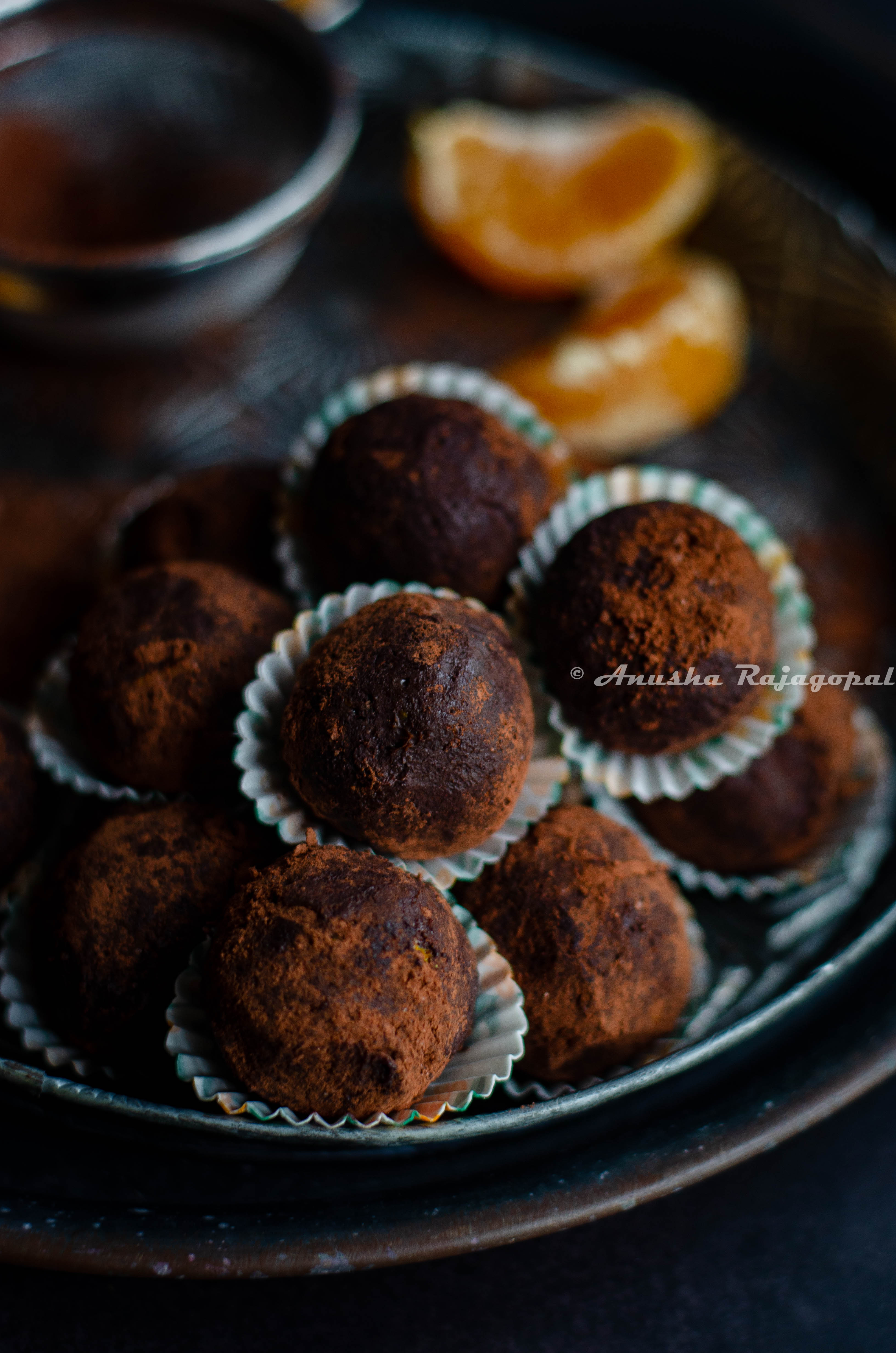 chocolate orange truffles in liners stacked on a vintage metal plate