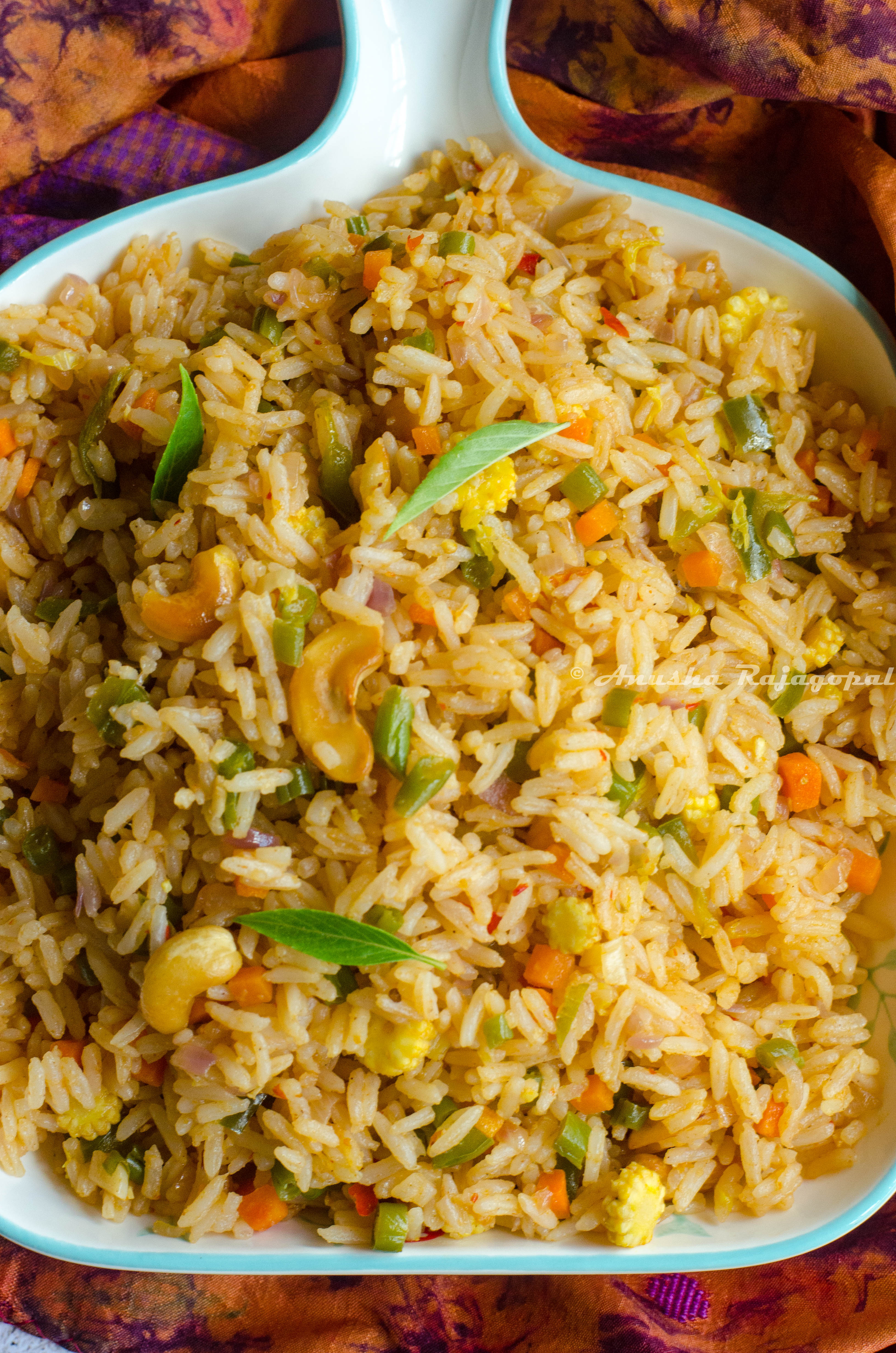 vegan thai basil fried rice served in a white platter placed on a tye dye napkin