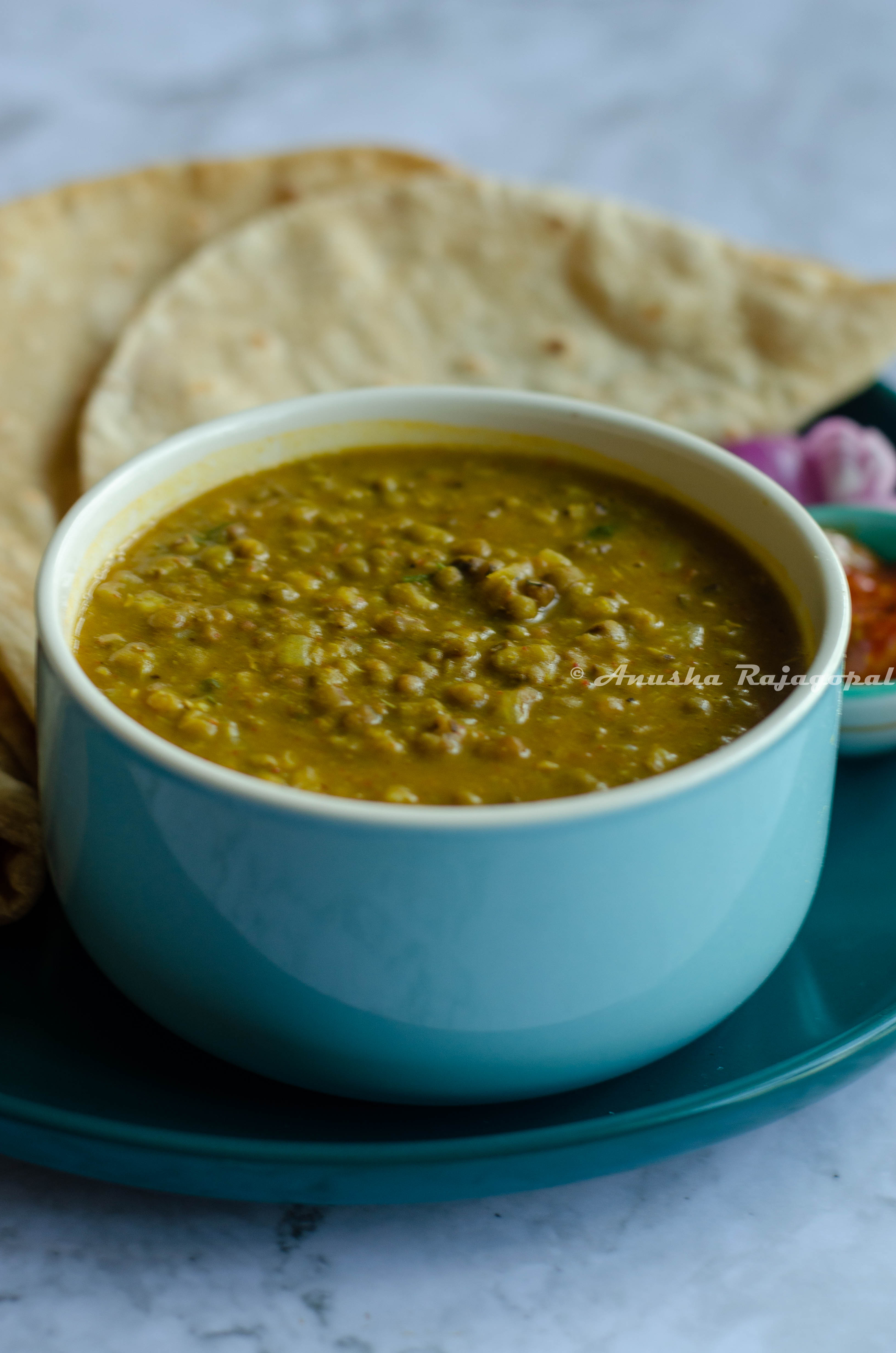 Instant pot green moong dal served in a blue bowl with rotis