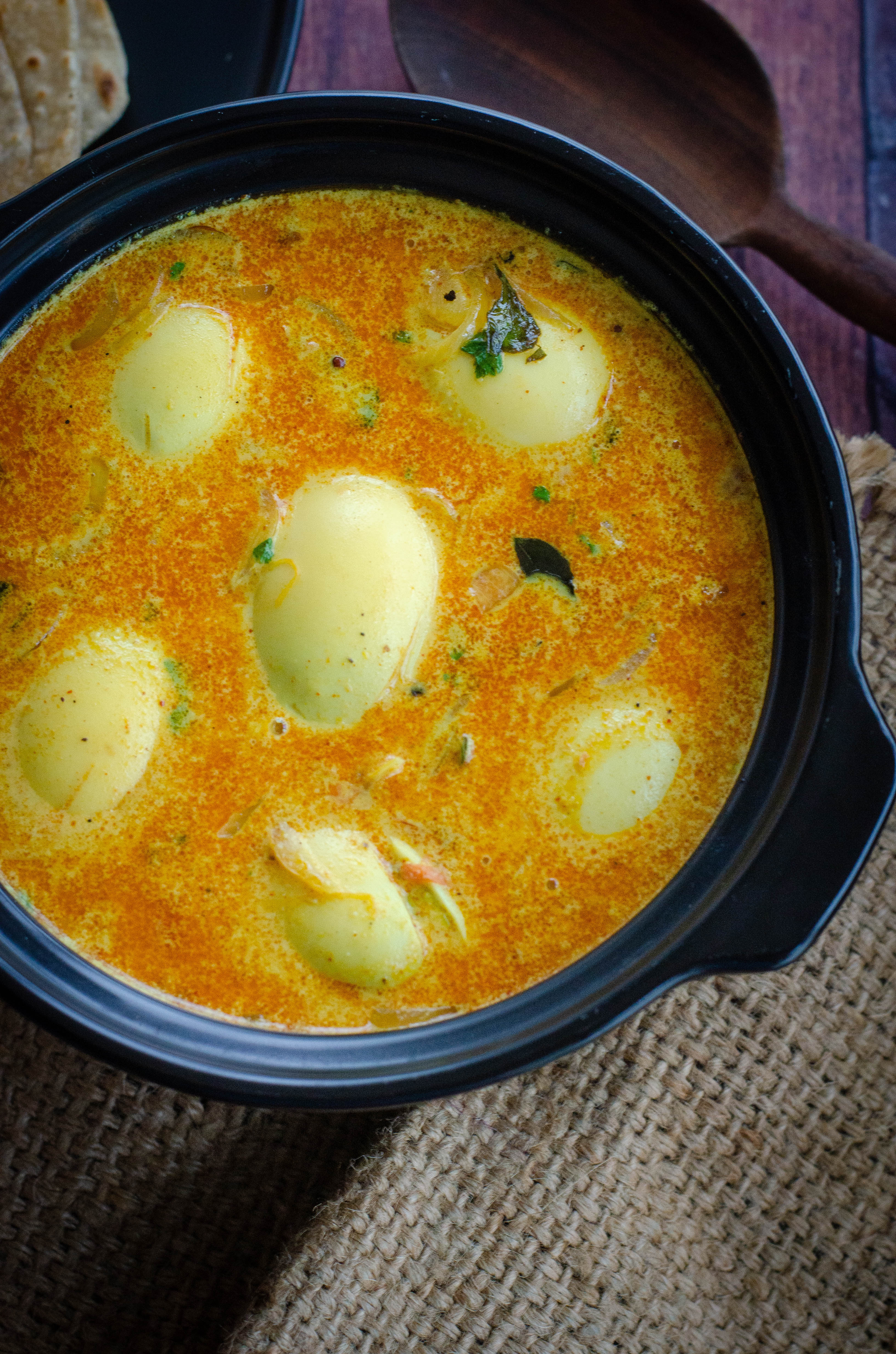 kerala egg curry served in a black bowl placed on a burlap mat
