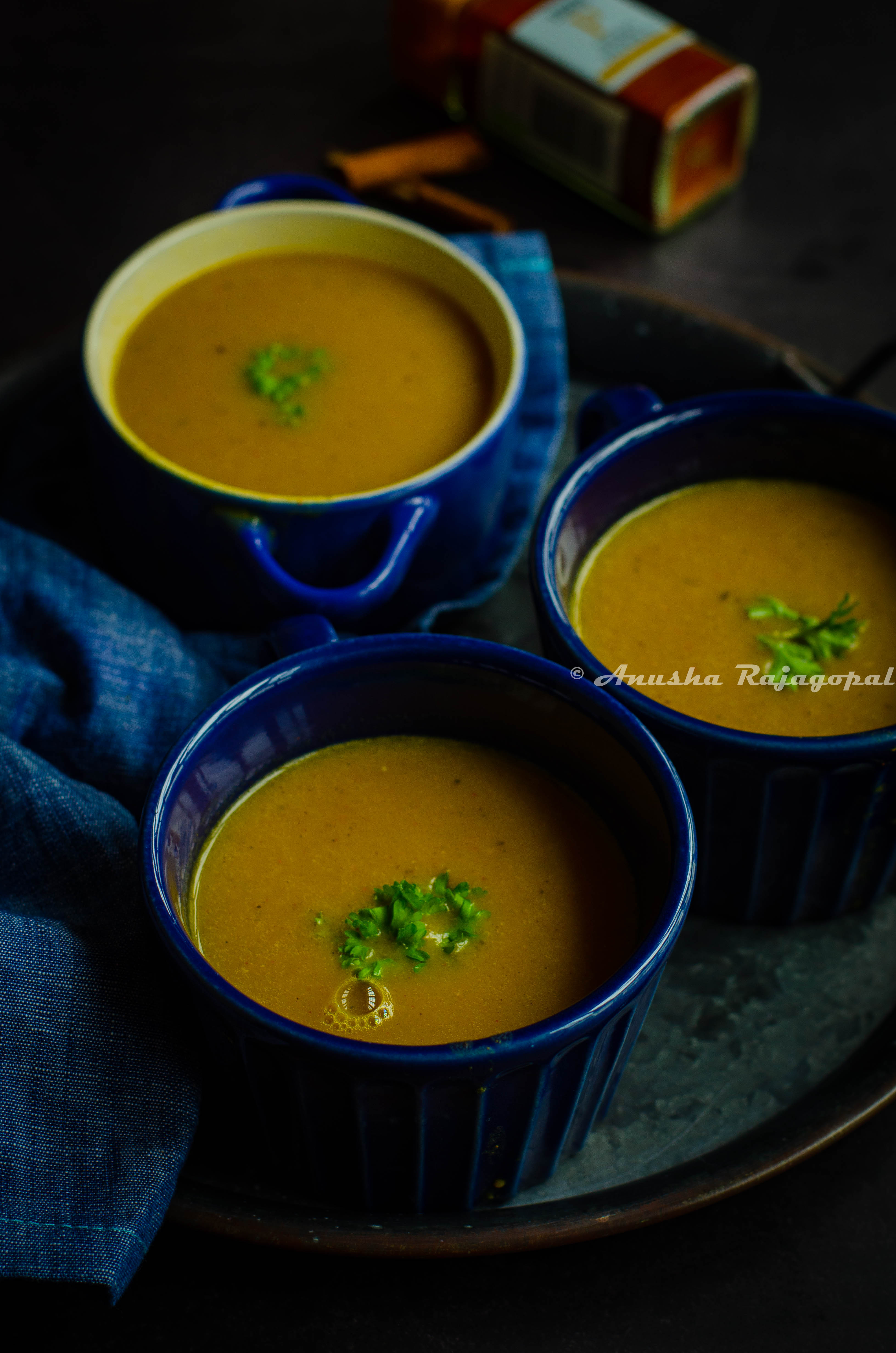 Moroccan red lentil soup served in blue soup bowls. Fresh parsley as a garnish on the top